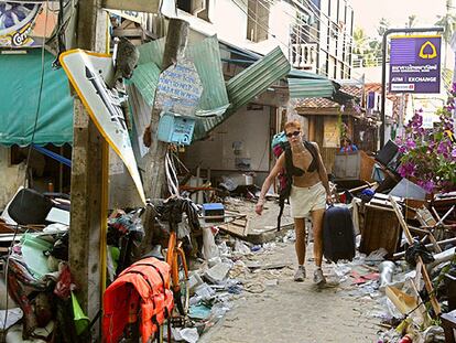 Una turista porta su equipaje por una calle devastada de la isla tailandesa de Phi Phi.