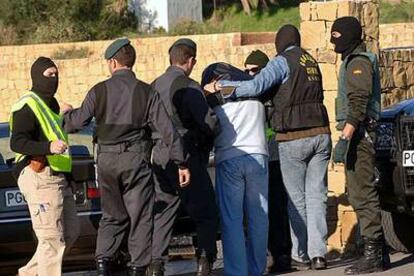 Guardias civiles rodean a uno de los detenidos antes de iniciar un registro en Estepona.