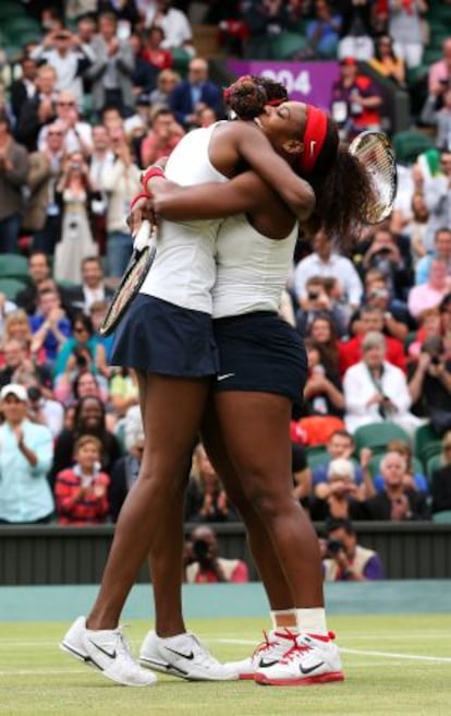 Venus y Serena Williams se abrazan tras un punto.