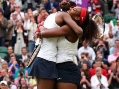 Venus y Serena Williams se abrazan tras un punto.