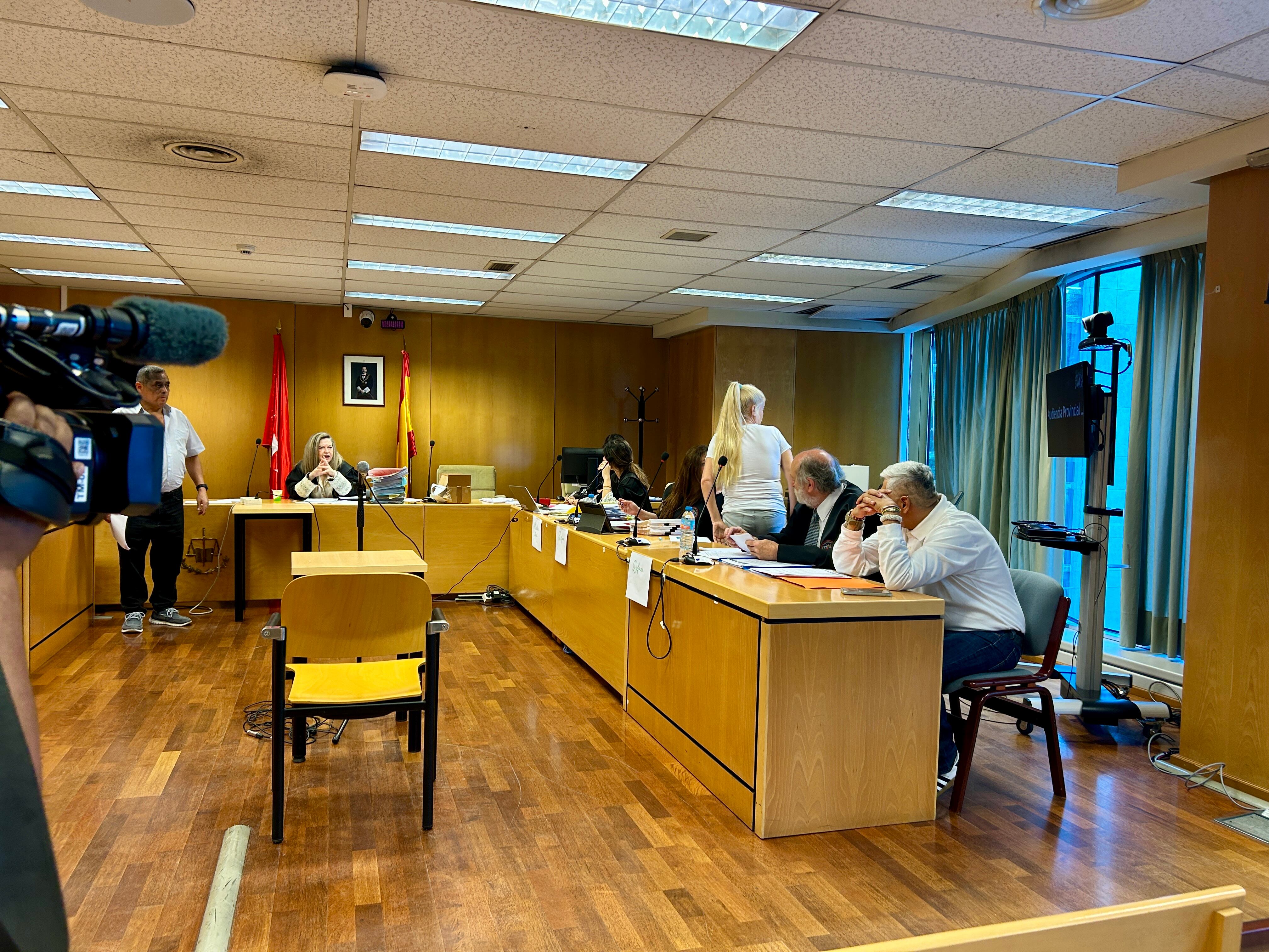 La acusada, de pie en la sala de juicios, y el acusado, en primer plano con la cara cubierta por su mano.