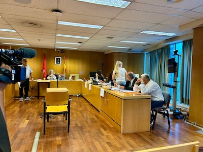 La acusada, de pie en la sala de juicios, y el acusado, en primer plano con la cara cubierta por su mano.
