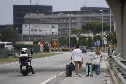 Una parella de turistes es dirigeix a peu a l'aeroport del Prat.