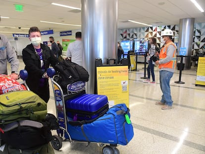 Unos viajeros pasan frente a un sitio de pruebas de covid-19 en el aeropuerto de Los Ángeles.