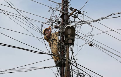 Un operario repara las lneas elctricas de un poste en Kochi (India).