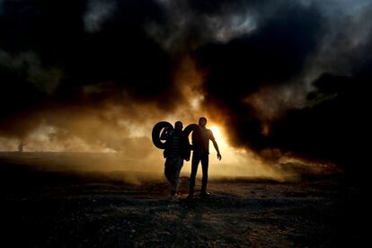 Dos palestinos entre el humo que emanan los neumáticos quemados en la frontera entre Israel y Gaza, el 12 de octubre de 2018.
 