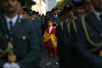 Un niño ataviado con una bandera de España, entre agentes de la Guardia Civil.