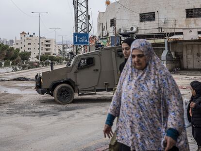 Several Palestinians walk past an Israeli military vehicle in Tulkarem, in the occupied West Bank, on Wednesday.