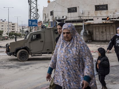 Varios palestinos pasaban por delante de un vehículo militar israelí en Tulkarem, en la Cisjornadia ocupada, el miércoles.