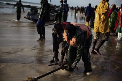 Un par de pescadores afirman el ancla de un cayuco durante la descarga manual de pescado en el puerto artesanal de Nuakchot.