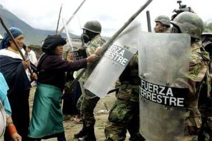 Varias mujeres golpean con palos a un grupo de soldados que bloquean una carretera en San Rafael, al norte de Quito.