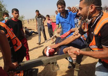 Manifestantes y médicos palestinos llevan a un hombre herido en una camilla.