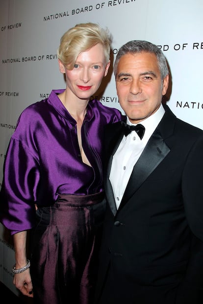 Tilda Swinton, en violeta y con un peinado muy masculino, al lado de George Clooney.