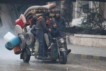 Un grupo de hombres, junto con sus enseres, huyen de Alepo.