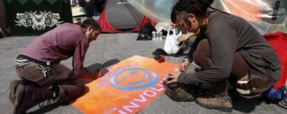 Dos 'acampados' en la Puerta del Sol preparan uno de los carteles.