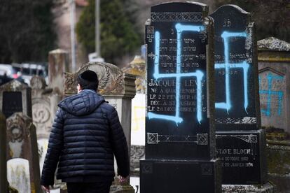 A man walks by graves vandalised with swastikas at the Jewish cemetery in Quatzenheim, on February 19, 2019, on the day of a nationwide marches against a rise in anti-Semitic attacks. - Around 80 graves have been vandalised at the Jewish cemetery in the village of Quatzenheim, close to the border with Germany in the Alsace region, which were discovered early February 19, 2019, according to a statement from the regional security office. (Photo by Frederick FLORIN / AFP)