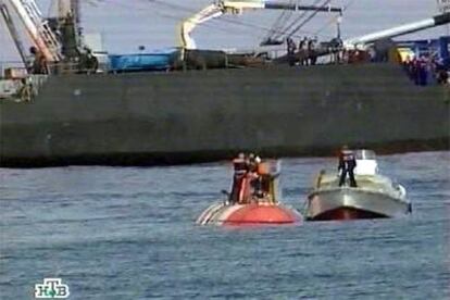 Una lancha de rescate se aproxima al pequeño submarino ruso (a la izquierda), con parte de su tripulación en la superficie.