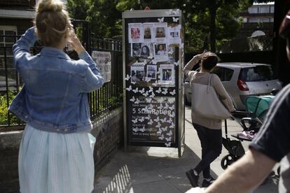 Una mujer hace una fotografía a un papel donde aparecen las personas desaparecidas del incendio, el 16 de junio.