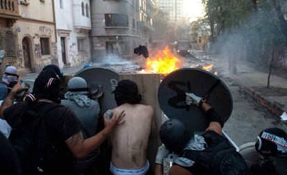 Un grupo de manifestantes se protegen con escudos improvisados durante los enfrentamientos con la policía en una protesta contra el presidente chileno, Sebastián Piñera, en Santiago de Chile.