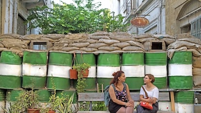 Eliza (a la izquierda) grecochipriota, y Ceyda, turcochipriota, frente a una parte del muro compuesto por bidones oxidados y sacos terreros en la parte griega de la capital. 