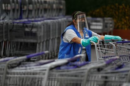 Trabajadora de supermercado desinfecta carros de compra.