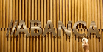 Un operario limpia en una oficina de Santiago de Compostela el logotipo de Abanca. EFE/Archivo