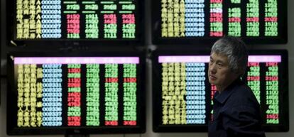 Un hombre pasa frente a pantallas con información financiera en China.