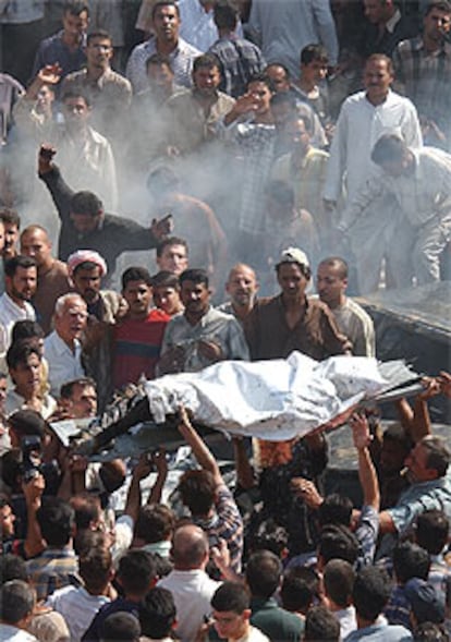 Voluntarios transportan el cadáver de un iraquí muerto por el estallido de un coche bomba en Bagdad.