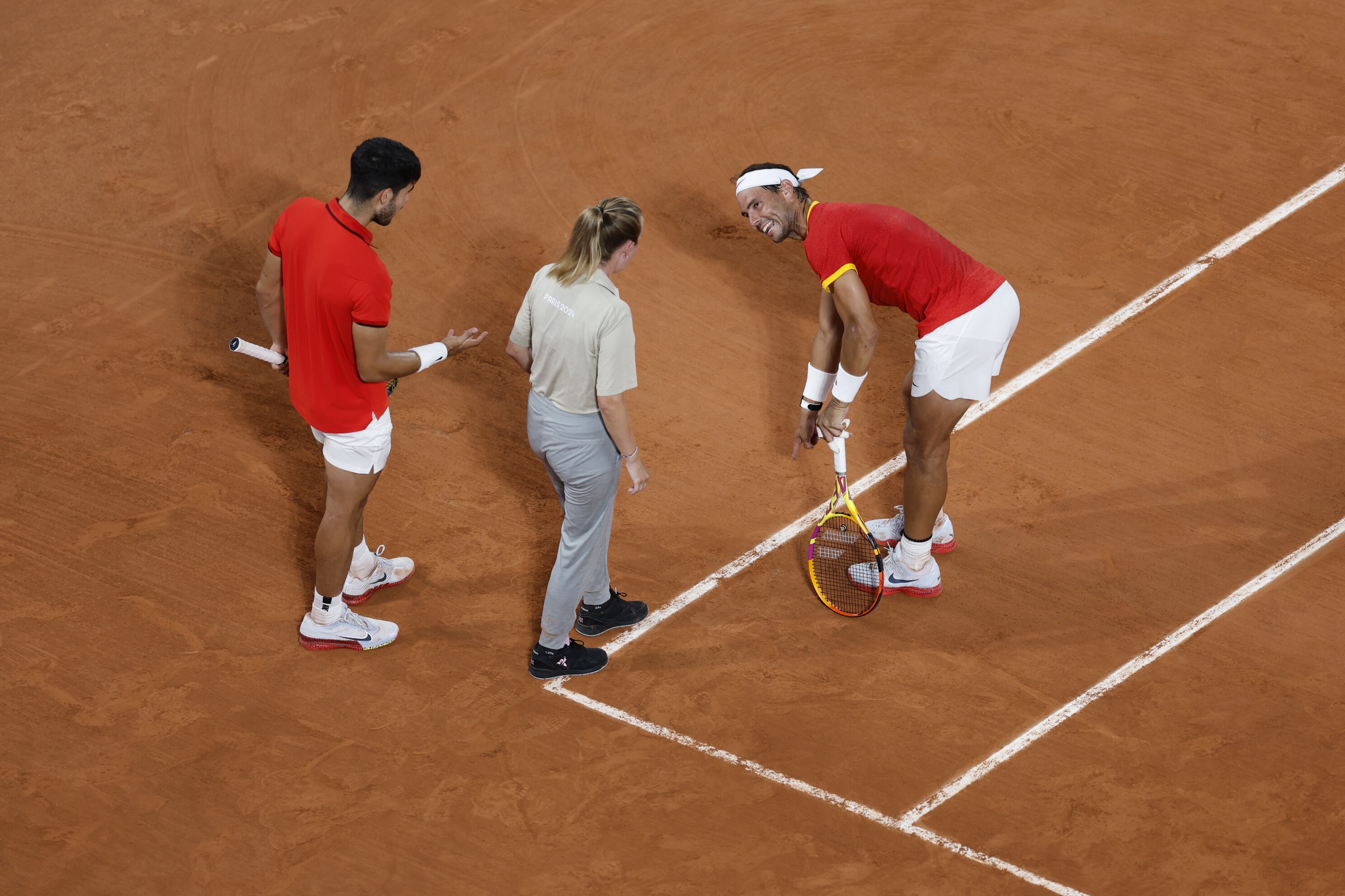 Rafa Nadal y Carlos Alcaraz conversan con la juez de línea durante los cuartos de final de dobles.