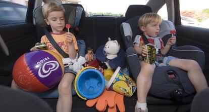 Dos niños viajan en la parte trasera de un coche.