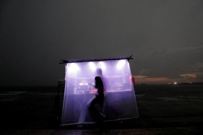 Un vendedor de comida rápida trabaja durante una noche lluviosa en Colombo (Sri Lanka), el 18 de abril de 2019.