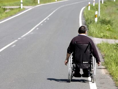 Una persona en silla de ruedas transita por una carretera a las afueras de Vitoria.