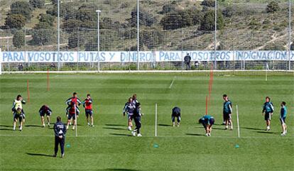 Los jugadores del Madrid se ejercitan durante el entrenamiento de ayer ante la pancarta que unas personas colgaron de la valla.