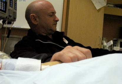 Mark Kelly, marido de la congresista Gabrielle Giffords, herida en la matanza de Tucson, agarra su mano junto a la cama del hospital.