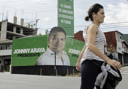 Una mujer camina frente a propaganda del candidato oficialista