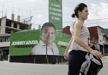 Mulher caminha em frente a propaganda do candidato do Governo.