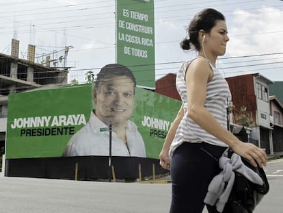 Mulher caminha em frente a propaganda do candidato do Governo.