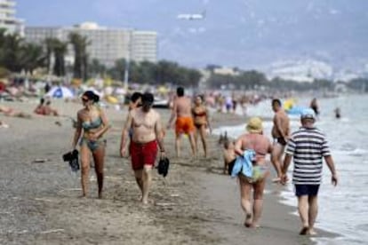 Varios turistas pasean por la orilla de la playa de El Bajondillo, en Torremolinos, Málaga. EFE/Archivo