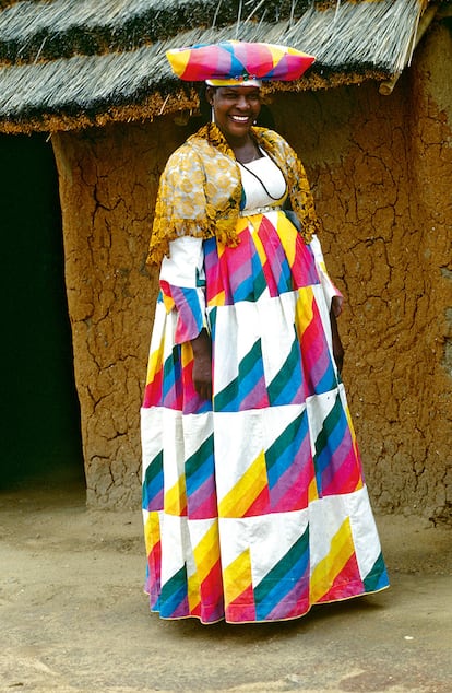 HERERO (NAMIBIA). La mujer herero de Otjiwarongo, a la izquierda, se viste con el ohorokova. El tocado u otjikalva recuerda a los cuernos del ganado, y es que los herero son un pueblo de pastores. En el pasado, los trajes se elaboraban en patchwork. Hoy aún los lucen las féminas de más edad. Es común poseer varios y se conservan con mimo para ser heredados.