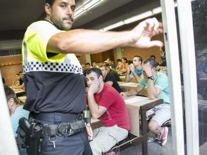 Un guarda urbano cierra la ventana de un aula, en la facultad de Economía de la UB, donde se realizó la prueba