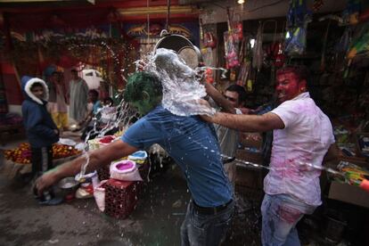 El precio del "gulal" oscila entre 20 y 50 rupias el kilo (unos 24 y 59 céntimos de euro), dependiendo de la calidad. En la imagen, un hombre es mojado en una calle de Jammu (India).