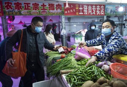 Ciudadanos de Wuhan hacen sus compras en un mercado local, tras la cuarentena impuesta a la ciudad foco de la infección del coronavirus. China ha confinado a casi 20 millones de personas en un intento de detener la propagación del virus.
