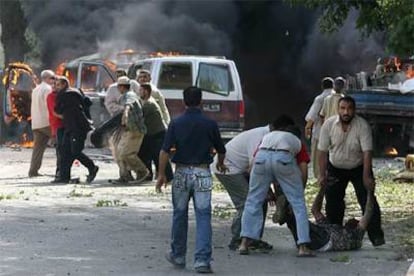 Ciudadanos iraquíes ayudan a trasladar a los heridos de la explosión de un coche bomba que ha causado la muerte de al menos catorce personas.