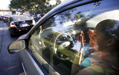 Una mujer se maquilla en el coche mientras espera en un atasco en el cruce fronterizo de Tijuana (México).