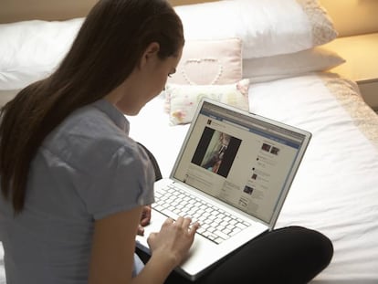 Un joven mira Facebook en su ordenador. 