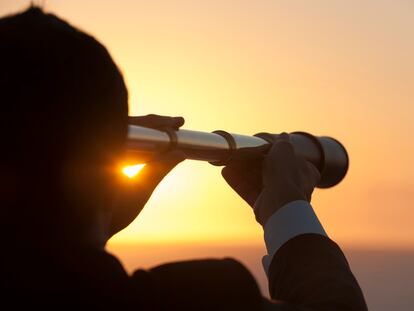 Hombre de negocios mirando con telescopio el horizonte