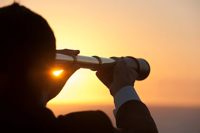 Hombre de negocios mirando con telescopio el horizonte