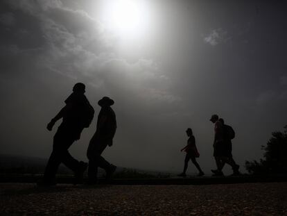 Varias personas caminan por la sierra de Córdoba, donde la calima tapa el sol y eleva las temperaturas, este domingo.