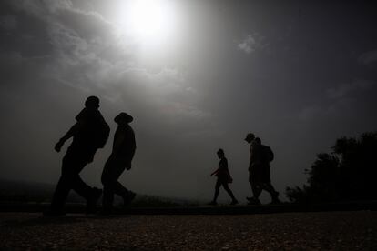 Varias personas caminan por la sierra de Córdoba, donde la calima tapa el sol y eleva las temperaturas, este domingo.