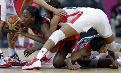 La canadiense Tamara Tatham (de rojo) lucha por la pelota contra las estadounidenses Seimone Augustus (centro) y Angel McCoughtry.